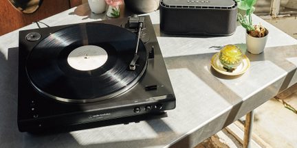 Sort Audio-Technica pladespiller, vinylplade i afspilning, set ovenfra på metalbord med højttaler