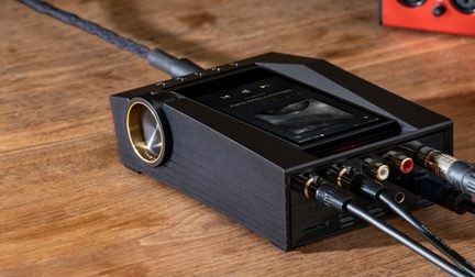 Přehrávač kazet černý, pohled zepředu a z boku, s připojenými audio kabely, na dřevěném povrchu