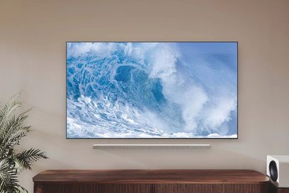 Samsung 65QN700B 2022 fladskærms-TV, der viser en blå brydende bølge, set forfra, stående på et træmøbel
