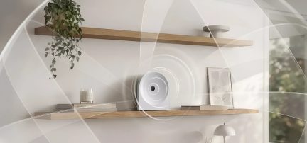 Diffusore di oli essenziali bianco dal design circolare su una mensola da parete in legno in un interno minimalista