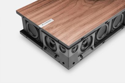 Trådløs tilsluttet højttaler Cambridge Audio EVO ONE, set fra en vinkel, med trætop og sider med flere sorte højttalere