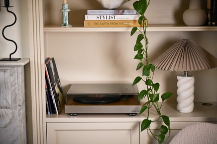 Gramofon Roberts w wykończeniu drewniano-metalowym z przyciemnionym pokrywą, widok z przodu na beżowej półce