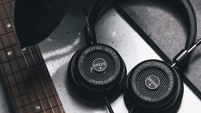 To åbne sorte Grado hovedtelefoner, den ene set forfra og den anden fra siden, placeret på en ridset metaloverflade