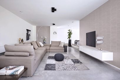 Sala de estar moderna com sofá bege, tapete cinzento, móveis brancos e pretos. Parede de tijolos brancos, iluminação embutida no teto