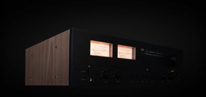 NAD C 3050 LE stereoforstærker, træfront, to baggrundsbelyste VU-metre, set forfra og let fra siden i mørke
