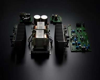 Widok z góry na srebrny, stereofoniczny wzmacniacz hi-fi Denon PMA-2500NE, z widocznymi wewnętrznymi komponentami elektronicznymi, w tym dwiema dużymi toroidalnymi transformatorami