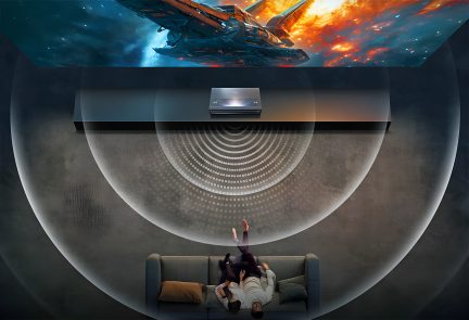 Top view, gray sofa with orange cushion, two people lying down, wall projector, image of a spaceship projected
