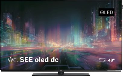 Loewe We. SEE oled dc 48 tuuman televisio edestä nähtynä, ohut musta näyttö kirkkaalla kaupunkimaisemalla ja OLED-logolla
