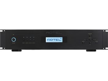 Rotel RMB-1555 melns daudzkanālu pastiprinātājs, priekšējais panelis ar pogām, ligzdām un zilu LCD displeju, kas rāda "ROTEL"