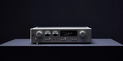 Stříbrný hi-fi zesilovač T+A při pohledu zepředu se dvěma ručičkovými VU metry, černým displejem a dvěma otočnými ovladači