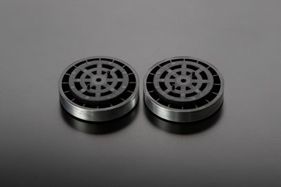 Two circular metal discs with black radial patterns on a gray background, viewed straight on against a plain gray surface