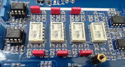 Modrá deska plošných spojů s elektronickými součástkami, kondenzátory a rezistory různých velikostí a barev