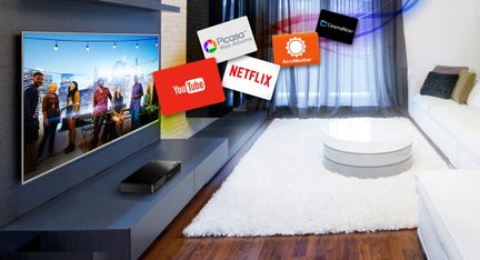 Tv-skærm, der viser streamingservice-logoer i en moderne stue med sofa og hvidt tæppe