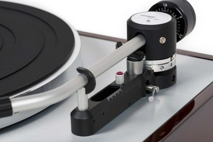 Nærbillede af sølvfarvet aluminiums-tonearm, sort graderet modvægt, sort base med skala, delvist pladetallerken