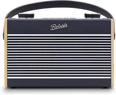 Přenosné rádio Roberts Rambler Max v tmavě modré barvě, pohled zepředu, obdélníkový plastový trup v tmavě modré barvě s žebrovaným předním panelem střídajícím tmavě modré a bílé pruhy, boční strany ze světlého dřeva, obloukovitá rukojeť z umělé kůže v laděné barvě s bílým prošitím a dva otočné knoflíky na horní straně.