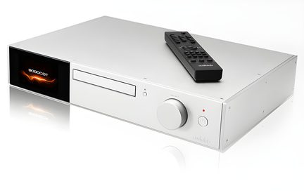 Lecteur CD argenté rectangulaire avec écran noir à gauche, bouton circulaire à droite, télécommande noire posée dessus