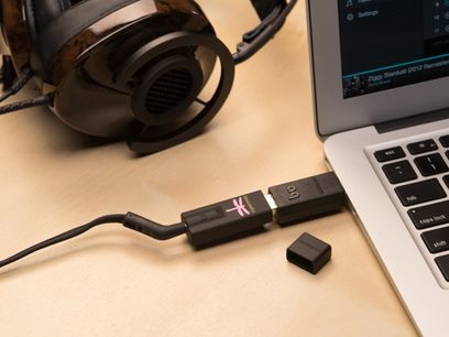 Audioquest DragonFly Black USB-lydkonverter, hovedtelefoner, USB-kabel og bærbar computer på et lyst træbord