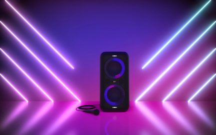 Trådløs sort højttaler med lilla LED-belysning, set forfra på en lilla neonbaggrund