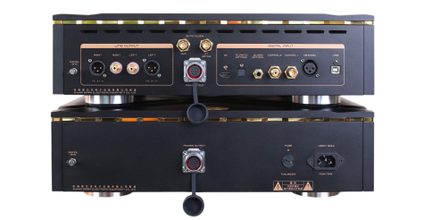 Dviejų viena ant kitos sukrautų matinės juodos spalvos hi-fi įrenginių galinis vaizdas su auksiniais apvadais, turinčių daugybę garso jungčių ir XLR, RCA, BNC, optinių, USB bei maitinimo lizdų.