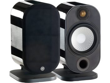 Kompat højtaler Monitor Audio Apex A10, sort lakeret kabinet med børstet metal sidepanel, set fra tre kvart forfra, der viser aftageligt tekstilgitter, gylden diskant, hvid højttaler med alveoleret overflade, kanterne frontbasrefleks og rektangulær grå sokkel