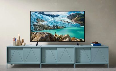 Samsung UE43RU7175-TV som viser et landskap med isbre og turkis innsjø, plassert på en lys blå TV-benk