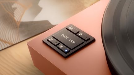 Korall vinylplade, sokkel med mat metal look, tæt på START·STOP-knapper, 33/45, afspilning, Bluetooth, blå LED