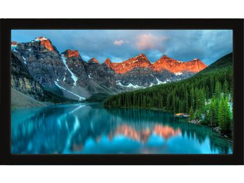 Horské jezero odrážející zasněžené skalnaté vrcholky osvětlené zapadajícím sluncem, obklopené jehličnatými lesy