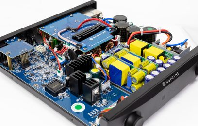 Innenansicht des integrierten Hi-Fi-Verstärkers Nuprime IDA-9, blaue Leiterplatte, schwarze Aluminium-Kühlkörper, gelbe Kondensatoren, Dreiviertelansicht