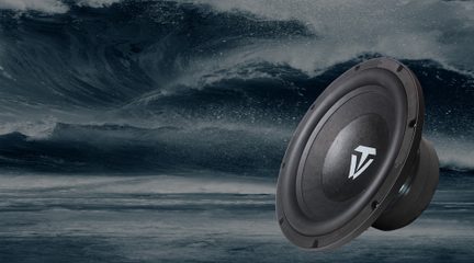 Sort subwoofer-højttaler med hvidt logo i vinkel mod baggrund af store blågrå havbølger