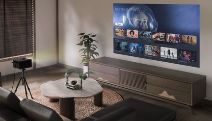 Salone moderno, proiettore nero su treppiede in metallo che proietta un'interfaccia video su una parete chiara, mobile TV in legno, vista obliqua