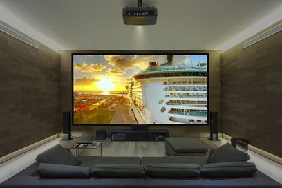 Optoma UHZ65 videoprojektor, der projicerer et billede af et krydstogtskib ved solnedgang i en moderne stue