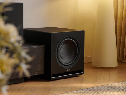Matte black subwoofer, rectangular enclosure, metal grille, front-facing port, three-quarter front view
