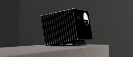 Carcasă electronică dreptunghiulară, neagră, din metal, prevăzută cu numeroase aripioare verticale argintii și o deschidere circulară lucioasă pe fațadă, așezată pe un suport mic, înclinat, vedere din perspectivă trei sferturi față.