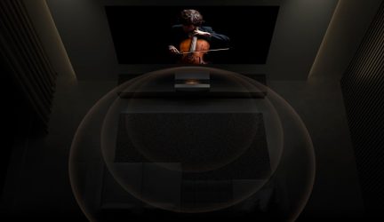 Cellist spiller på scenen i mørket, set bagfra, oplyst af en spotlys ovenfra