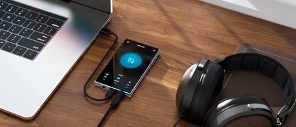 DAC USB portatile con schermo blu collegato a un computer portatile e a cuffie audio nere