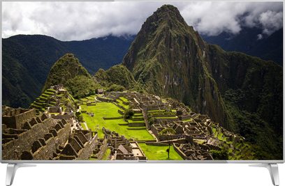 Luftfoto af Machu Picchu, en ruinby fra inkariget i Peru, omgivet af frodige bjerge under en skyet himmel