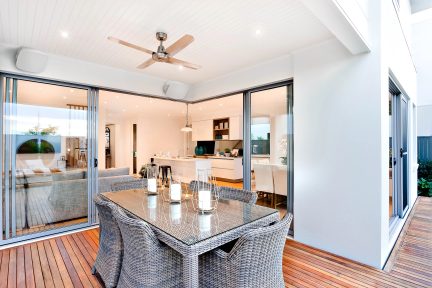 Modern huisinterieur met open woonkamer en keuken, houten eettafel, grijze bank, ramen van vloer tot plafond, perspectiefweergave