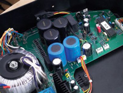 Circuit imprimé vert avec composants électroniques variés : condensateurs bleus et noirs, résistances, fils multicolores