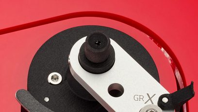 Lähikuva ylhäältä katsottuna Vertere Acoustics Pack DGX Sabre Lite -levysoittimen harjatusta alumiinista, vaahtomuovista ja mustasta muovista valmistetusta moottorimekanismista punaisella akryylirungolla
