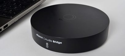Elipson Audio Bridge netværksaudioafspiller, sort, set oppefra, flad cylindrisk kabinet med centralt logo