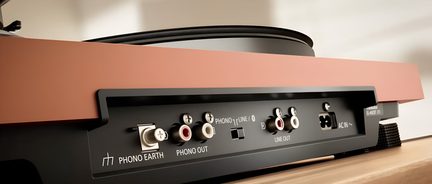 Pladeforstærker i træ og plast med brun-orange vinylfinish, bagside, RCA phono/line-porte, jordskrue, strømstik