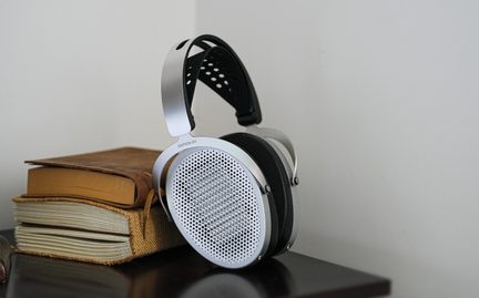 Auriculares plateados de metal, cápsulas con rejilla abierta perforada, almohadillas negras, diadema negra perforada, vista en tres cuartos