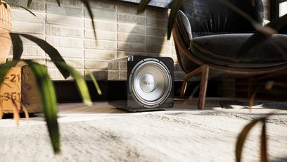 SVS SB-1000 PRO subwoofer i sort lak, set forfra, placeret på gulvet mellem en brun læderstol og en grøn plante