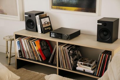 Amplificatore hi-fi integrato stereo Cambridge Audio EVO 150SE nero in metallo spazzolato visto di tre quarti dall’alto, chassis rettangolare sottile con fianchi grigliati, pannello frontale con schermo a colori a sinistra e ampia manopola argentata a destra, posizionato su una mensola