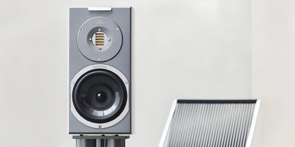 Kompakt, rektangulær sølvgrå højttaler med metalfront, set forfra, med indbygget gyldent bånddiskant i en øvre metalcirkel og sort woofer med sølvkant nederst