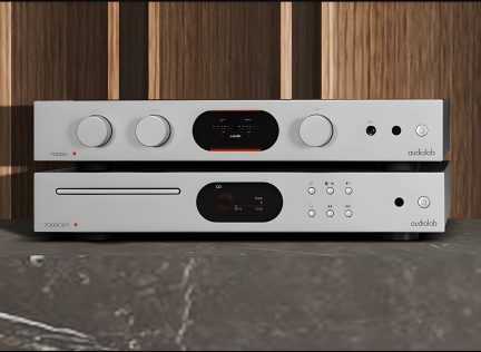 Dos dispositivos de audio apilados en metal gris con botones, pantallas negras, inscripciones "audiolab" y fondo de madera vertical