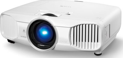 Epson EH-TW7200 hvid videoprojektor, set lidt fra siden forfra, linse med blåt lys, ventilationsgitre