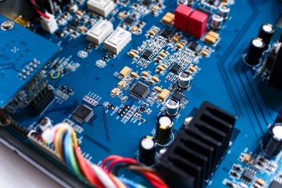 Blå printplade med forskellige elektroniske komponenter såsom kondensatorer og modstande, tæt ovenfra-billede