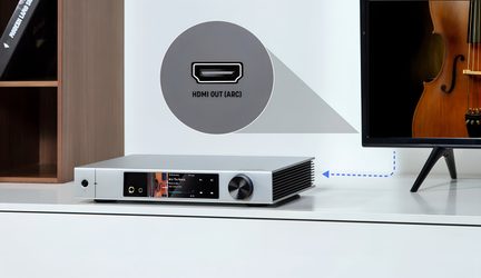 Silverfärgad ljudspelare i borstad aluminium, snedställd framifrån, front med färgskärm, två hörlursuttag och en stor svart ratt, svarta sidomonterade kylflänsar samt inzoomad ruta som visar HDMI ARC-utgången