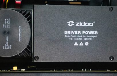 Sort Zidoo Driver Power-elektronikboks med stik og advarsel "Risiko for elektrisk stød, må ikke åbnes!"
